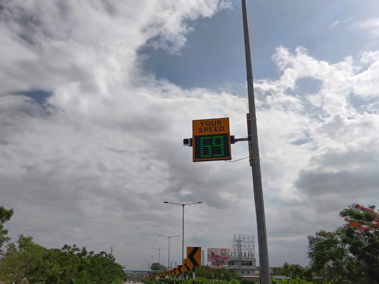 CAIPL 3-Digit radar speed display installed on a highway, showing an approaching vehicle 69 km/h in green LEDs with the radar sensor mounted alongside on the same pole